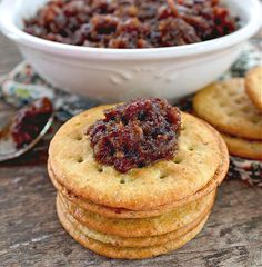 there is a bowl of jelly on top of crackers next to some other cookies