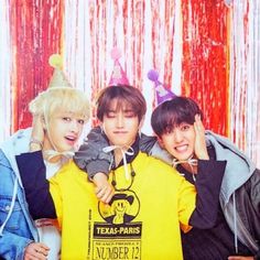 three young men standing next to each other in front of a photo booth with balloons and streamers