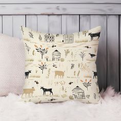 a white pillow with black animals and trees on it, sitting on a fur covered bed