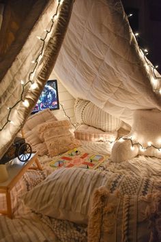 a bed covered in blankets and lights under a tent