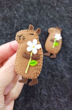 someone is holding two small felt animals with flowers on them