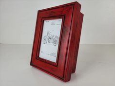 a wooden frame with a drawing on the front and bottom is shown in red wood