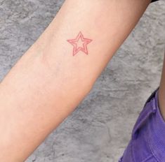 a woman's arm with a small star tattoo on the left side of her arm