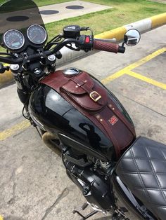 a black motorcycle with a brown leather bag on it's seat