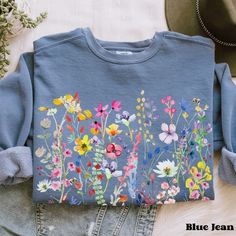 Elevate your style with this delightful and vibrant sweatshirt featuring a stunning spring and summer wildflowers design. Each sweatshirt is carefully crafted to infuse a touch of nature into your wardrobe. The colorful wildflowers burst with life, creating a sense of warmth and joy. This sweatshirt is a perfect blend of style and comfort, making it an ideal addition to your wardrobe. Whether you're going for a walk in the park, a cozy evening in, or simply want to express your love for wildflow Cotton Floral Print Sweatshirt For Fall, Spring Crew Neck Sweatshirt With Plant Print, Floral Print Spring Sweatshirt, Spring Plants Print Cotton Sweatshirt, Spring Floral Embroidery Long Sleeve Sweatshirt, Spring Cotton Sweatshirt With Plant Print, Spring Long Sleeve Sweatshirt With Floral Embroidery, Spring Floral Embroidered Long Sleeve Sweatshirt, Spring Bohemian Cotton Sweatshirt