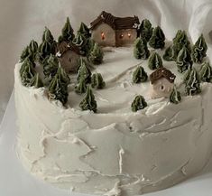 a white frosted cake with trees and houses on top