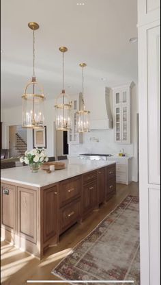 a large kitchen with an island and chandelier hanging from it's ceiling