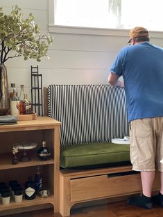 a man standing on top of a couch next to a wooden shelf filled with bottles