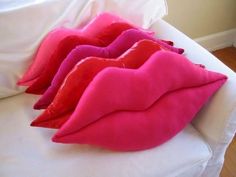 three pink pillows sitting on top of a white couch