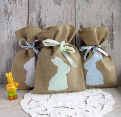 three burlap bags with bunny silhouettes on them sitting next to a small toy rabbit