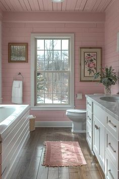 a bathroom with pink painted walls and wood flooring, along with a white bathtub