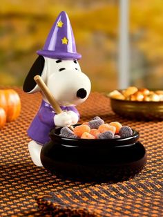 a figurine of a dog dressed as a witch scooping candy into a bowl