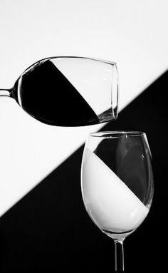 a wine glass with white wine being poured into it, in front of a black and white background