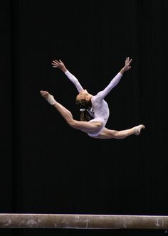 a woman is performing on the balance beam