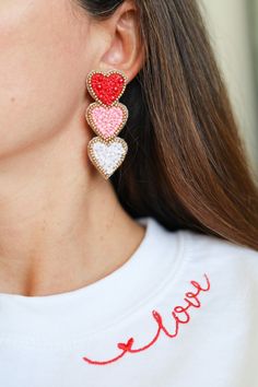 a woman wearing two heart shaped earrings