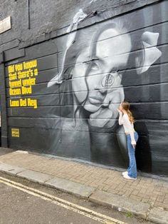 a woman standing in front of a wall with a painting on it's side