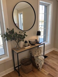 a living room with a mirror, plant and two wicker baskets