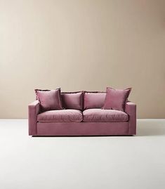 a pink couch sitting on top of a white floor next to a brown and beige wall