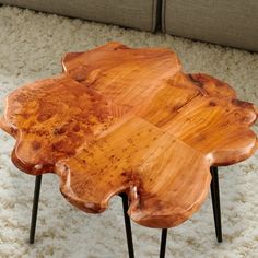 a coffee table made out of wood on top of a white carpeted floor next to a couch