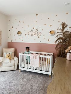 a baby's room with pink walls and gold polka dot decals