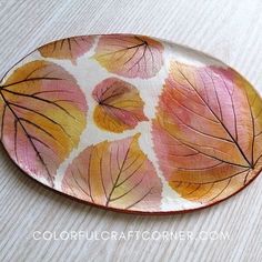 a plate with leaves painted on it sitting on a table