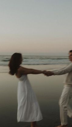 two people holding hands while walking on the beach