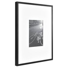 a black and white photo with a bicycle on the road in front of it is framed