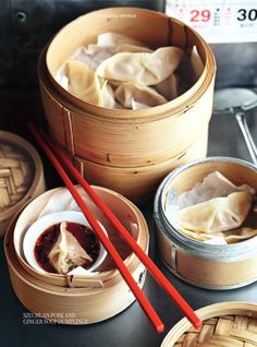 three wooden containers filled with dumplings and chopsticks on top of a table