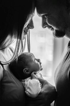 a man and woman holding a baby in their arms