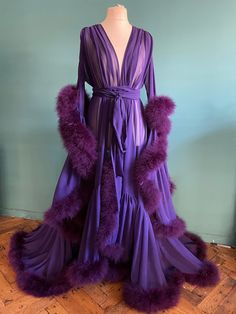 Beautiful chiffon dressing gown in Aubergine.  Trimmed along the hem and the sleeve edges with fluffy marabou feathers.  Ties around the waist with a matching chiffon belt.  One size fits all due to the design and fullness of the robe.  Perfect for family gatherings, walking the dogs as well as taking out the rubbish.  Please expect some feathers to shed - no one can look this fabulous without losing a few feathers. Fluffy Dressing Gown Aesthetic, Dead Husband Robe, Long Sleeve Feather Robe For Parties, Purple Feathered Dress For Evening, Dressing Gown Aesthetic, Dopamine Room, Fancy Robe, House Gown, Violet Gown