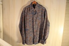 "This is a rare vintage long sleeve men's disco style shirt by Chemi Et Cie. It has all over pattern in blues and browns, no pockets. It has seven plastic buttons down the front, and two on each cuff (one was missing and has been replaced and does not match). 100% Polyester. Tag Size: Large 16 1/2 My Measurements: shoulder- 19 1/2\", pit to pit- 23\", arm- 25\", back- 29 1/2\" Origin: Korea Maker: Chemi Et Cie Year: 1970's Condition: great, pre-owned, miner wear, loose threads, and distress, one Retro Brown Long Sleeve Shirt, Retro Long Sleeve Shirt With Vintage Pattern, Vintage Patterned Long Sleeve Shirt, Long Sleeve Shirt With Retro Print, Vintage Long Sleeve Patterned Shirt, Long Sleeve Shirt With Retro Print For Fall, Fitted Long Sleeve Shirt With Retro Print, Blue Long Sleeve Shirt With Vintage Print, Fall Long Sleeve Shirt With Retro Print