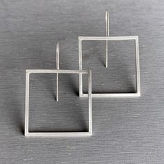 "These sleek silver earrings are all about geometry. The square silver hoops are created from square sterling silver wire giving them a very modernist feel. The squares are 1-1/4\" x 1-1/4\", and the ear wires add 3/4\" making the earrings 2\" long. Bright satin finish. Made to order just for you. Please allow 1-2 weeks after payment has cleared for item to ship. Thank you! ----------------------- PACKAGING All items arrive in a gift box so they are ready for giving. Shipped to your doorstep wel Modern Square Hoop Earrings For Everyday, Minimalist Silver Rectangular Earrings, Minimalist Square Hoop Earrings For Everyday, Modern Square Single Earring, Modern Sterling Silver Square Jewelry, Modern Square Sterling Silver Jewelry, Nickel-free Square Minimalist Earrings, Silver Square Everyday Earrings, Minimalist Square Nickel-free Earrings