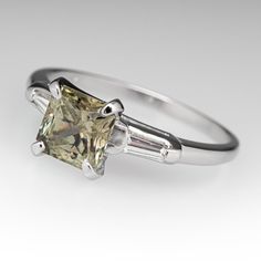 This gorgeous yellow sapphire engagement ring is centered with a cut cornered square cut Montana sapphire that we sourced and set in a vintage platinum diamond mounting. The shoulders are each channel set with a tapered baguette cut diamond. The ring measures 7.5mm at the top, rises 7.8mm above the finger, tapering to 1.5mm wide and 0.9mm thick at the base of the shank. The ring is currently a size 7.5 and we offer complimentary sizing to fit. Classic Gia Certified Rectangular Sapphire Ring, Classic Gia Certified Sapphire Princess Cut Ring, Classic Gia Certified Princess Cut Sapphire Ring, Classic Gia Certified Square Cut Sapphire Ring, Blue Square Cut Platinum Ring, Blue Square-cut Platinum Ring, Luxury Emerald-cut Sapphire Ring With Tension Setting, Luxury Square-cut Sapphire Ring With Diamonds, Yellow Sapphire Ring Engagement