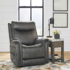 a gray recliner chair sitting on top of a rug in front of a window