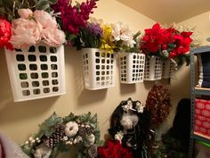 flowers are hanging on the wall next to baskets with wreaths and pine cones in them