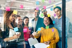 a group of people standing in front of a window with post it notes on them