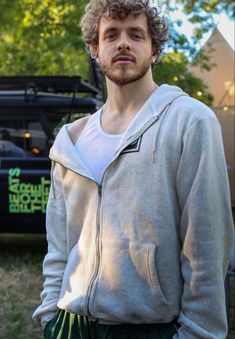 a man standing in front of a truck with his head turned to the side and looking at the camera