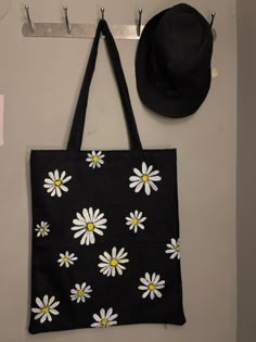 Black tote with white daisies! What else do y’all need order yours now. Link given below. Black Tote Bag Painting Ideas, Black Tote Bag Design Ideas, Black Tote Bag Design, Diy Wall Hanging Crafts, Tote Bag Business, Jute Handbags