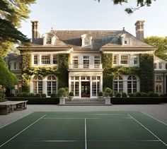 a tennis court in front of a large house