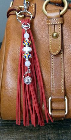 a brown leather purse with tassels and beads hanging from the handle, on top of a wooden table