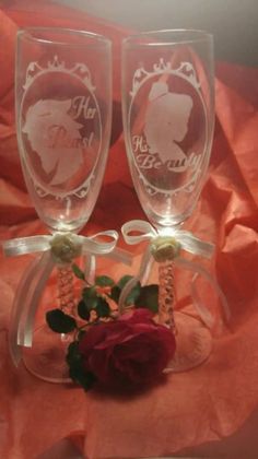 two wine glasses sitting on top of each other with a rose in front of them