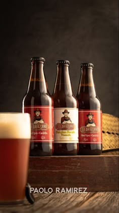 three bottles of beer sitting on top of a wooden table