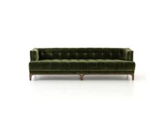 a green velvet couch with wooden legs