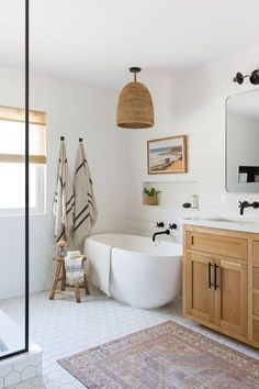 a white bath tub sitting next to a wooden cabinet in a bathroom under a light fixture