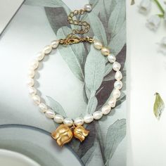 This Lily Of The Valley Pearl Bracelet is a luxurious gift for any special occasion. The timeless design of this exquisite accessory is perfect for any woman's personal style and features beautiful blooms of lily of the valley. A gift of extraordinary elegance, it will be sure to make the recipient feel celebrated and cherished on their special day.  DETAILS Materials:   18K Gold on Brass, Freshwater Pearl Measurements: Length: 17.83"(45.3cm) + Extender: 1.97"(5.0cm) Weight:   5.4 g Choose a lil Lily Of The Valley Accessories, Lily Of The Valley Bracelet, Lily Of The Valley Jewelry Ring, Elegant Gold Plated Flower-shaped Bracelet, Lily Of The Valley Brooch, Pearl Charm Bracelet, Lily Of The Valley Flowers, Cat Pendant Necklace, Mermaid Pendant