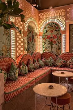 an ornately decorated room with red and orange couches, tables and stools