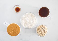 ingredients for peanut butter and oatmeal in bowls on a marble countertop