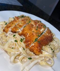 a white plate topped with pasta covered in sauce and chicken schnitzel toppings