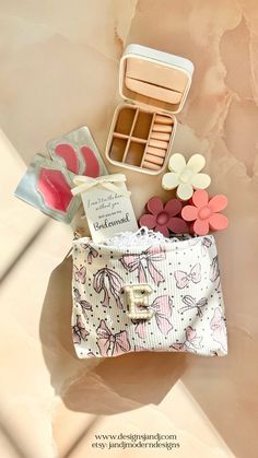 the contents of a small purse are laid out on top of a table with pink and white flowers