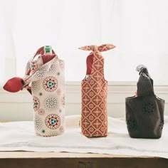 three vases sitting on top of a bed in front of a window with curtains